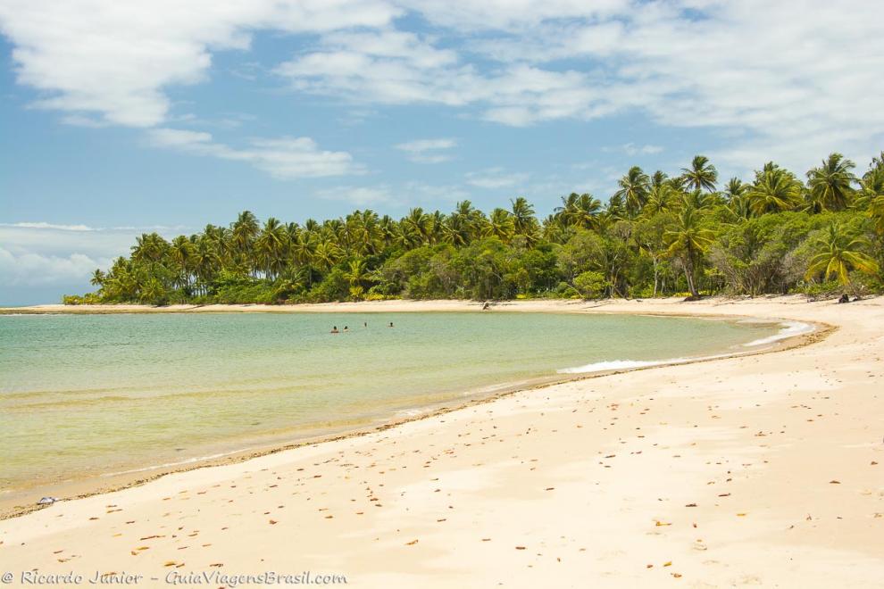 Imagem do mar e pessoas ao fundo mergulhando na belíssima praia.